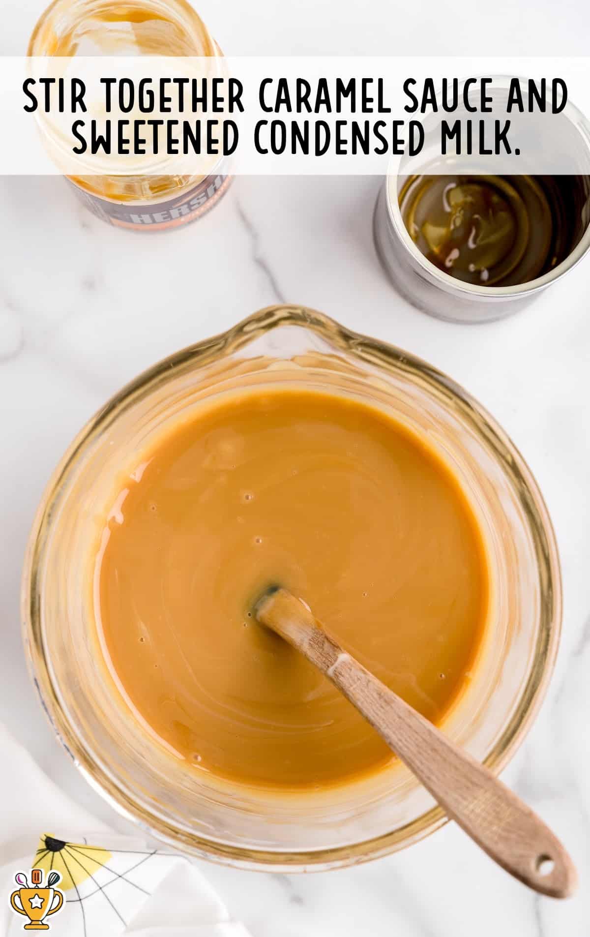 Caramel sauce and sweetened condensed milk mixed together in a bowl with a wooden spoon in it