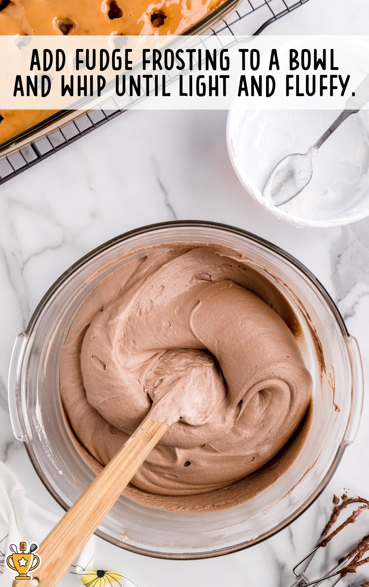 Fudge added into a bowl of other Turtle Poke Cake ingredients and whipped