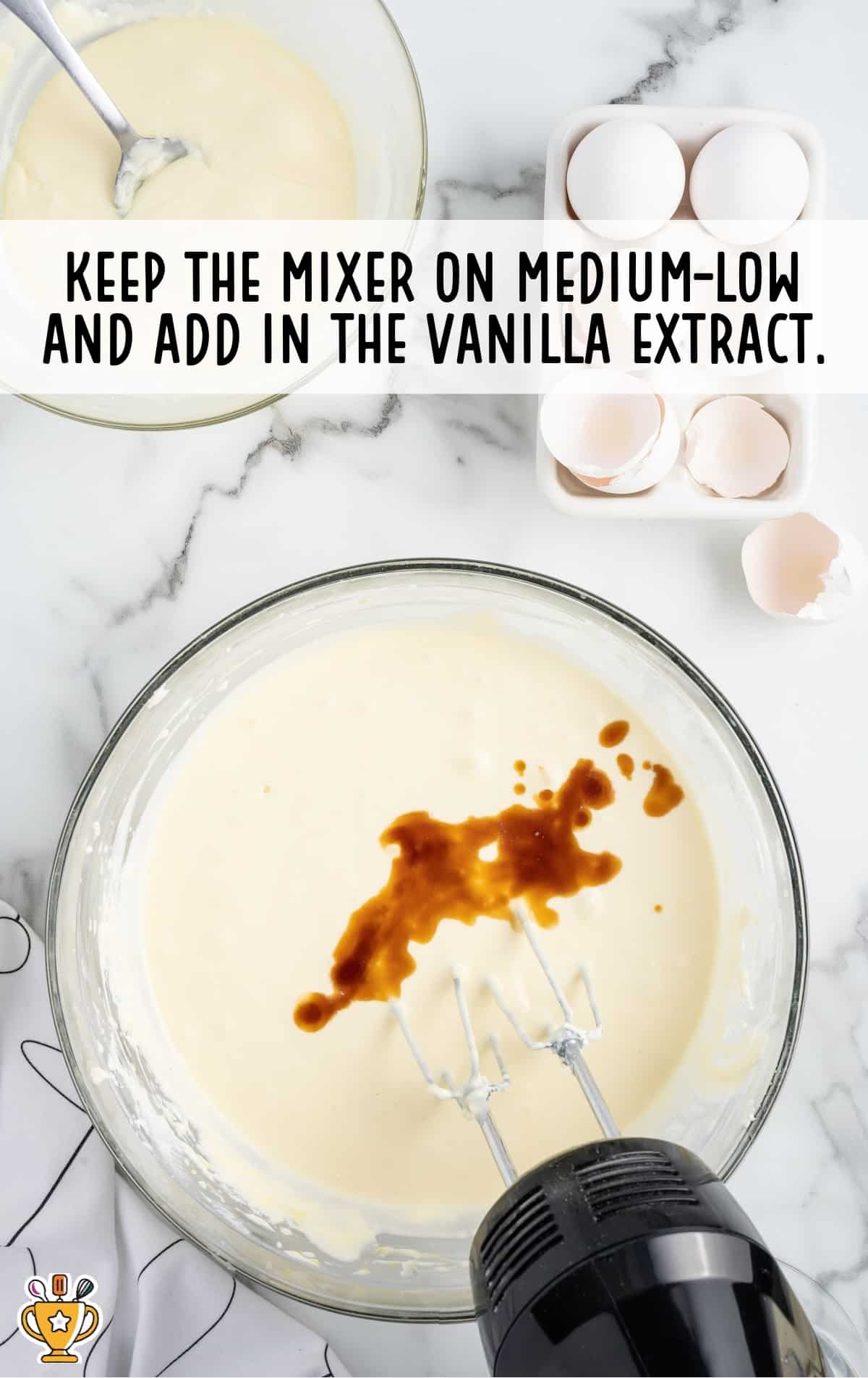 vanilla added in a bowl with the mixture , and a mixer inside the bowl