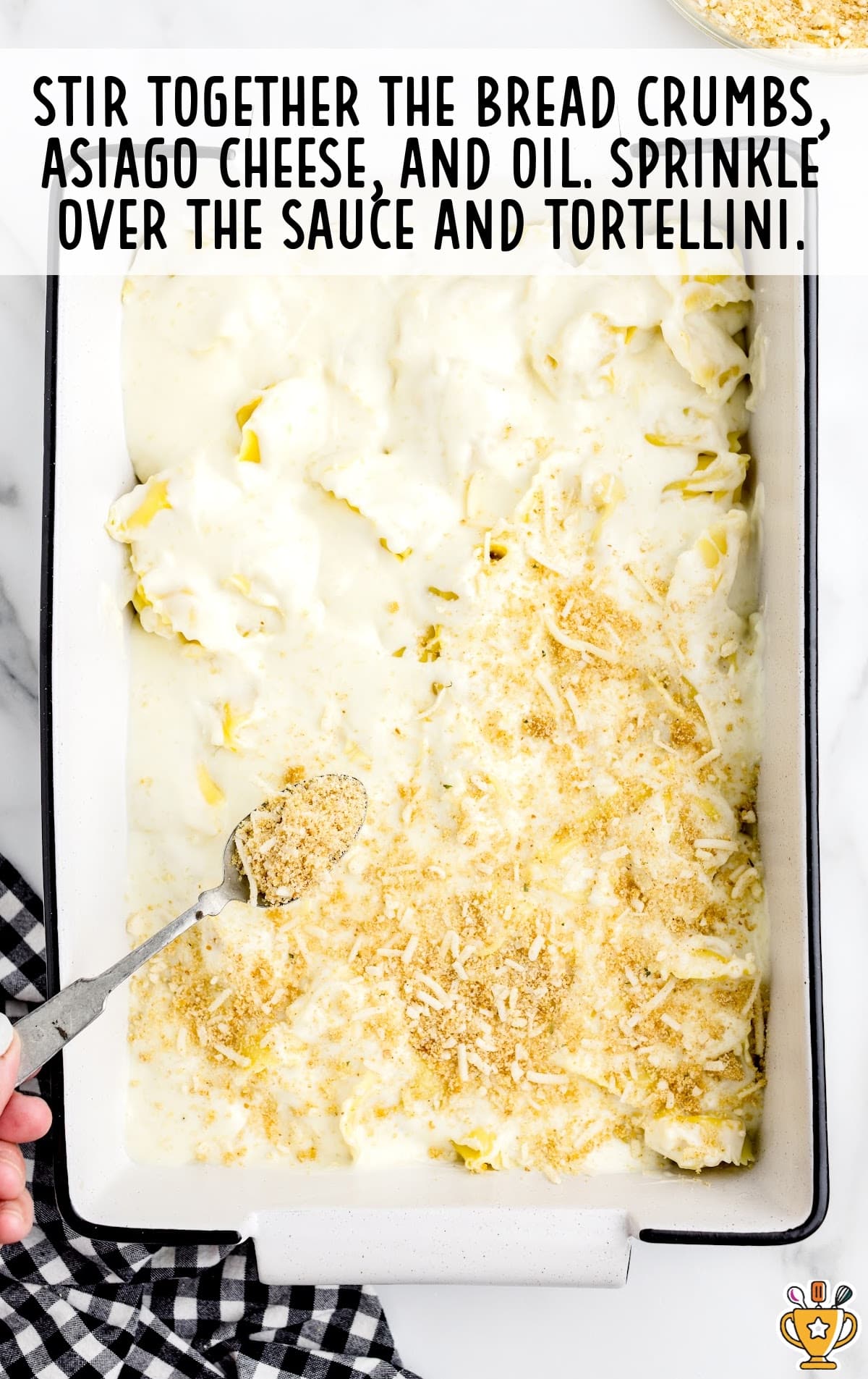 Bread crumbs, asiago cheese and oil sprinkled over the sauce and tortellini in a baking pan
