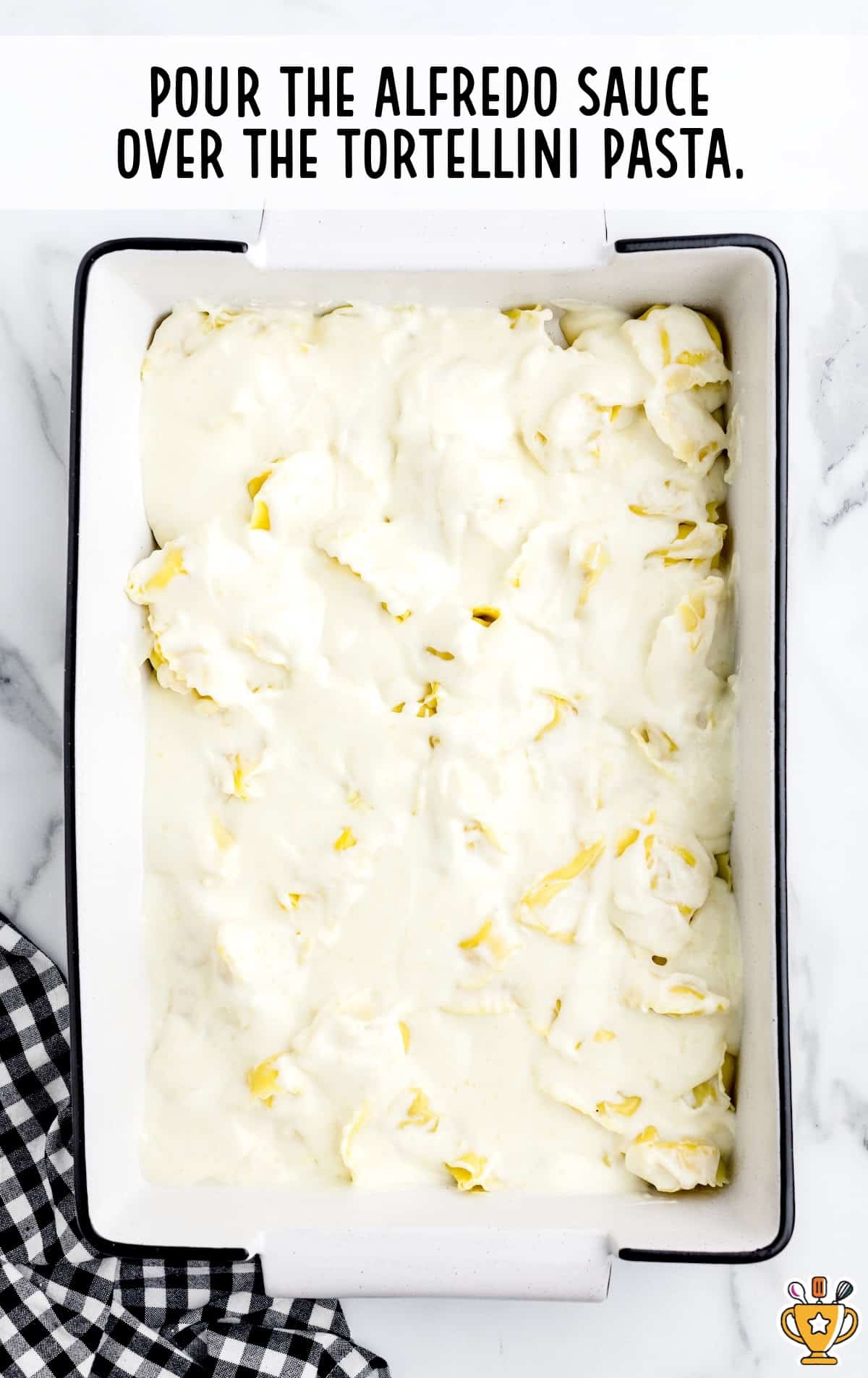 Alfredo sauce over tortellini pasta in a baking pan