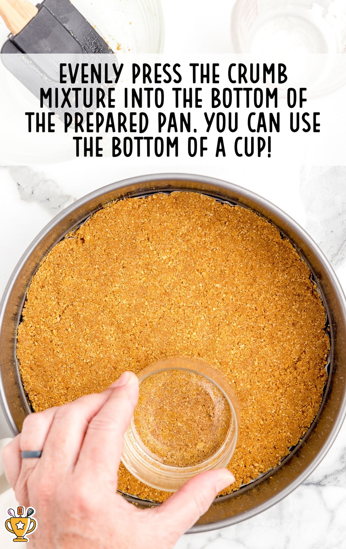 crumb mixture pressed into a pan by a hand holding a cup