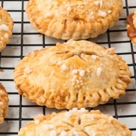 A cooling rack covered in freshly baked air fryer apple hand pies.