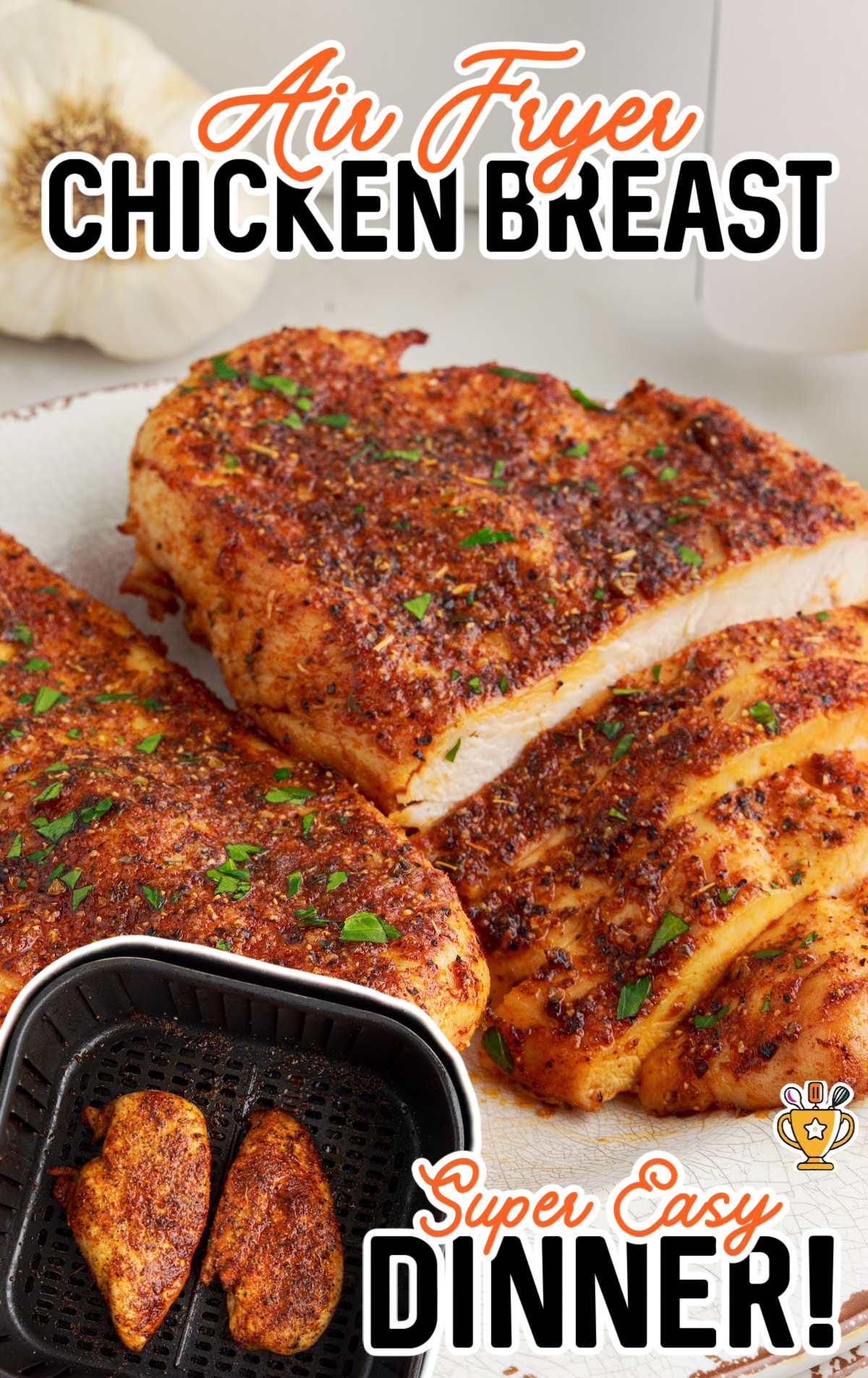Air Fryer Chicken Breasts on a white plate near an air fryer basket full of chicken.