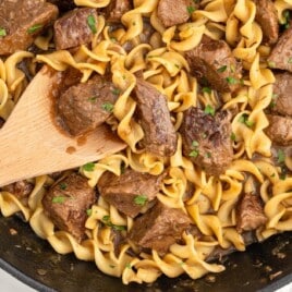 Beef Noodles in a skillet with a wooden spoon in it