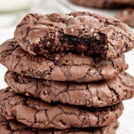 a stack of brownie cookies. the top one has a bite out of it.