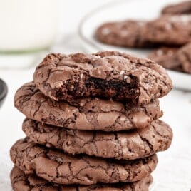A stack of brownie cookies with a bite out of the top one.