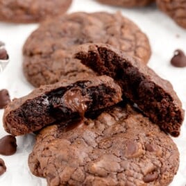 Brownie mix cookies on parchment paper, one broken in half.
