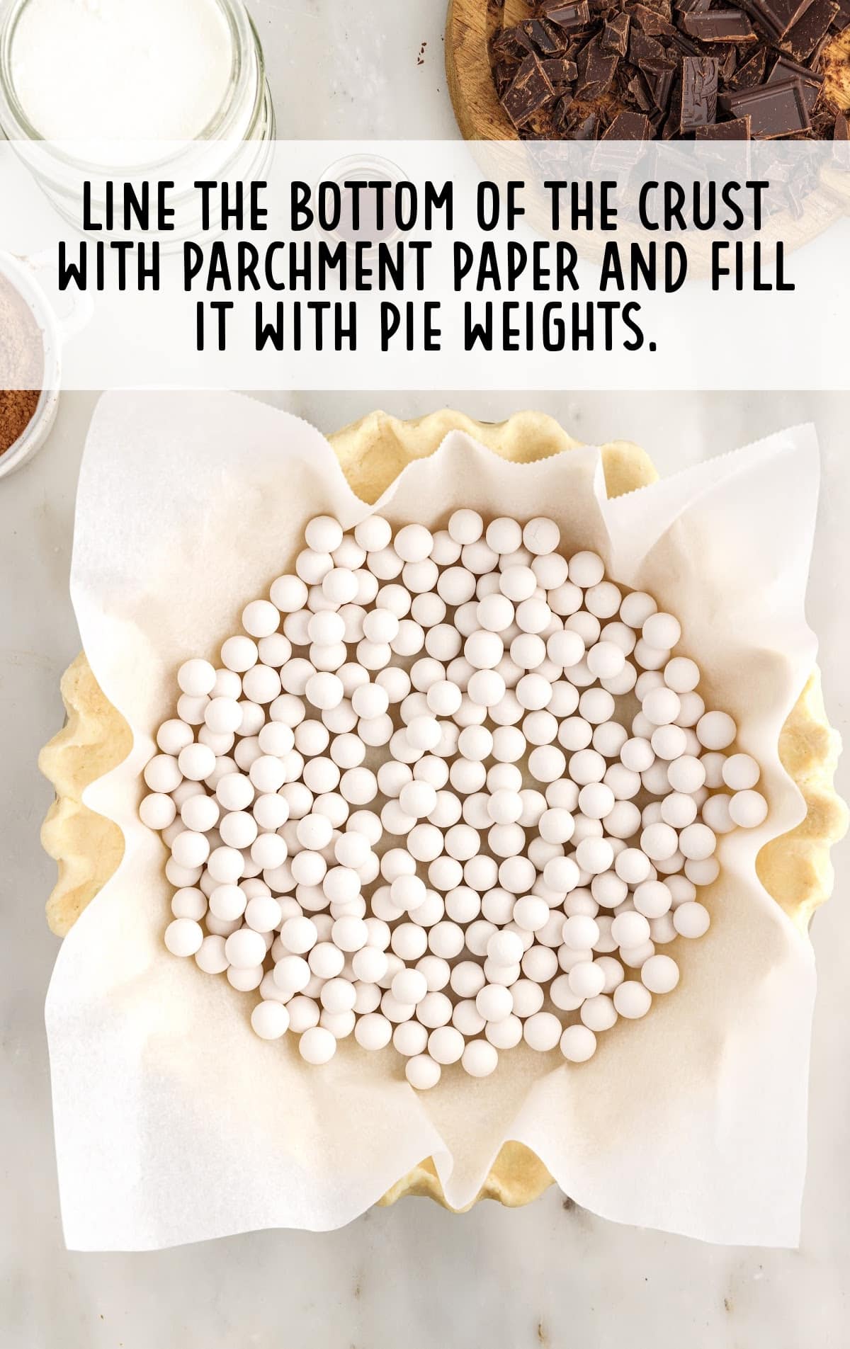 A pie crust with parchment paper and the pie weights on it