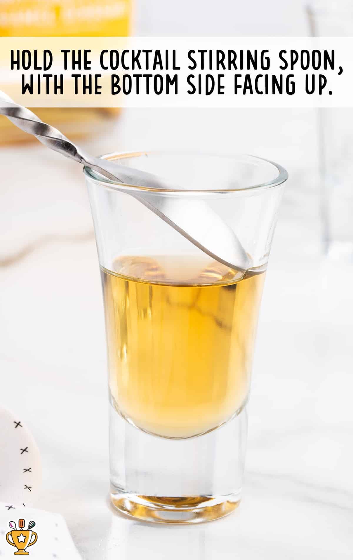 cocktail stirring spoon held into a glass of Buttery Nipple Shot