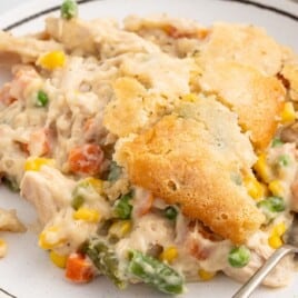 A serving of chicken cobbler on a white plate with a fork.