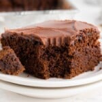 A piece of chocolate cake on a white plate with a bite missing from it.