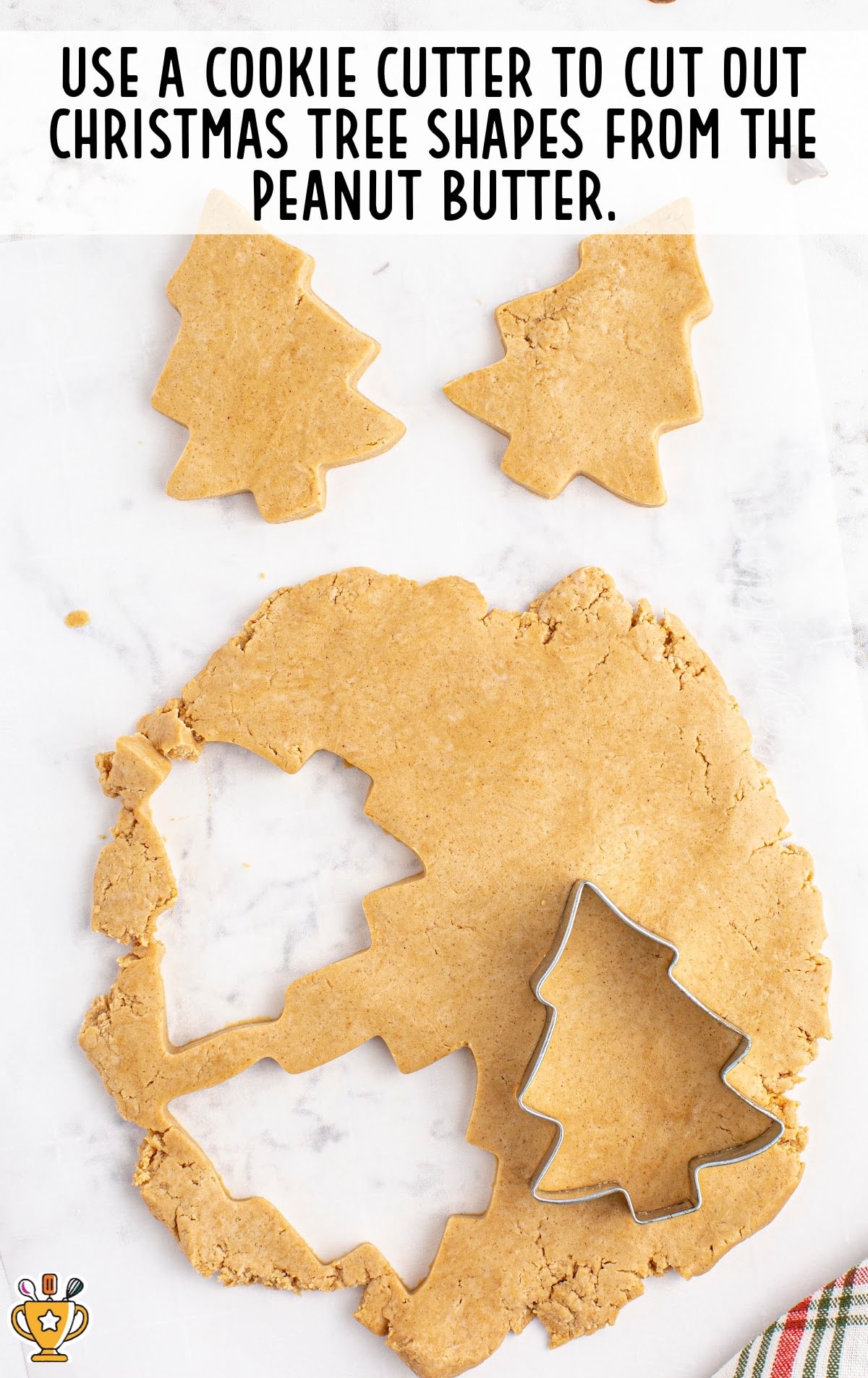peanut butter with a cookie cutter, cutting out some Christmas Tree shapes cookies