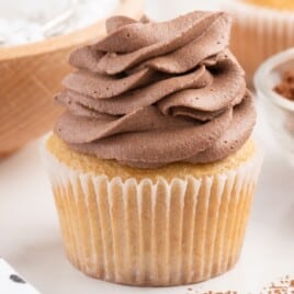 a vanilla cupcake covered in chocolate whipped cream.