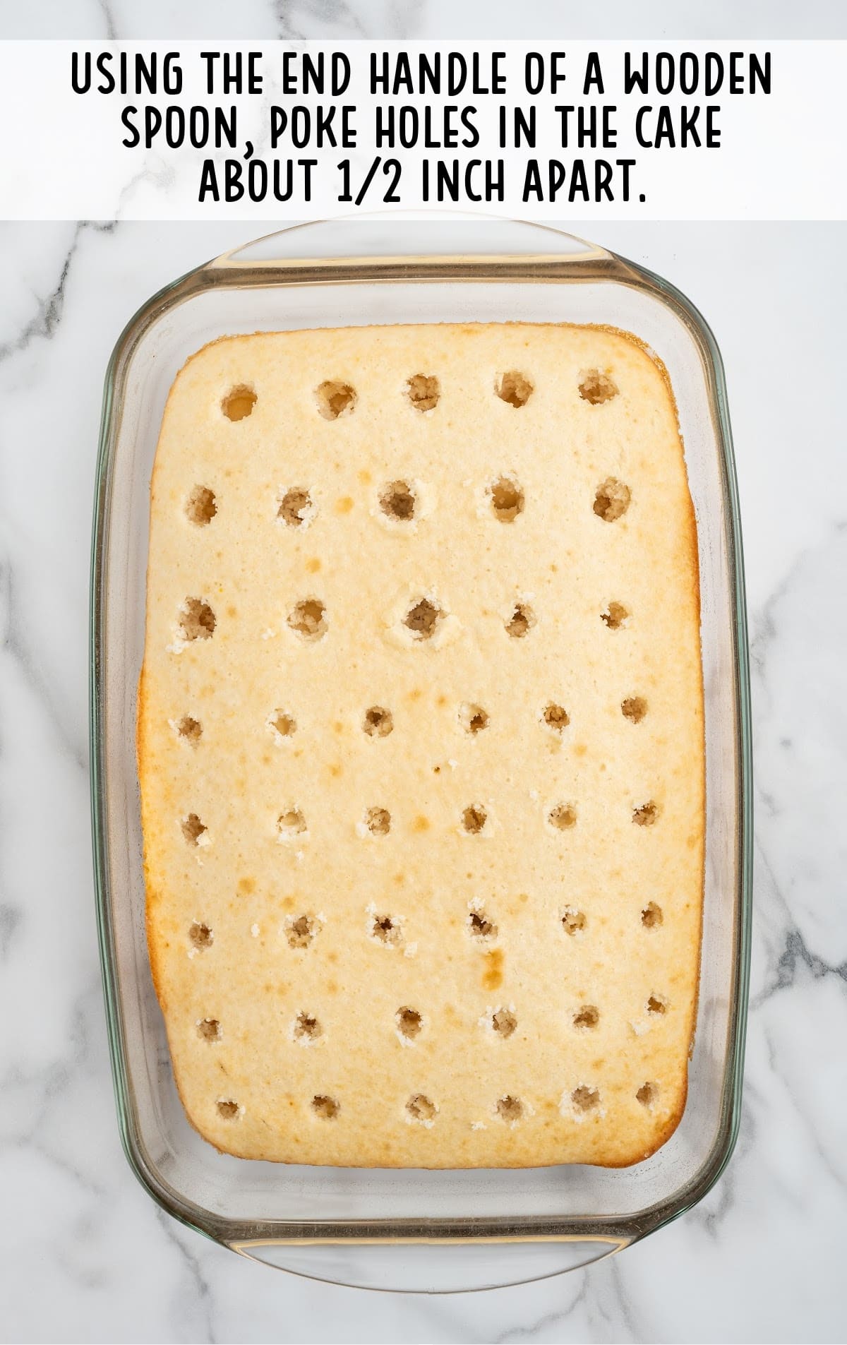 A cake in a glass baking pan with holes on it