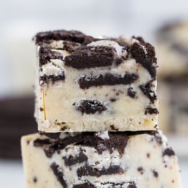 Two pieces of cookies and cream fudge sitting on top of one another.
