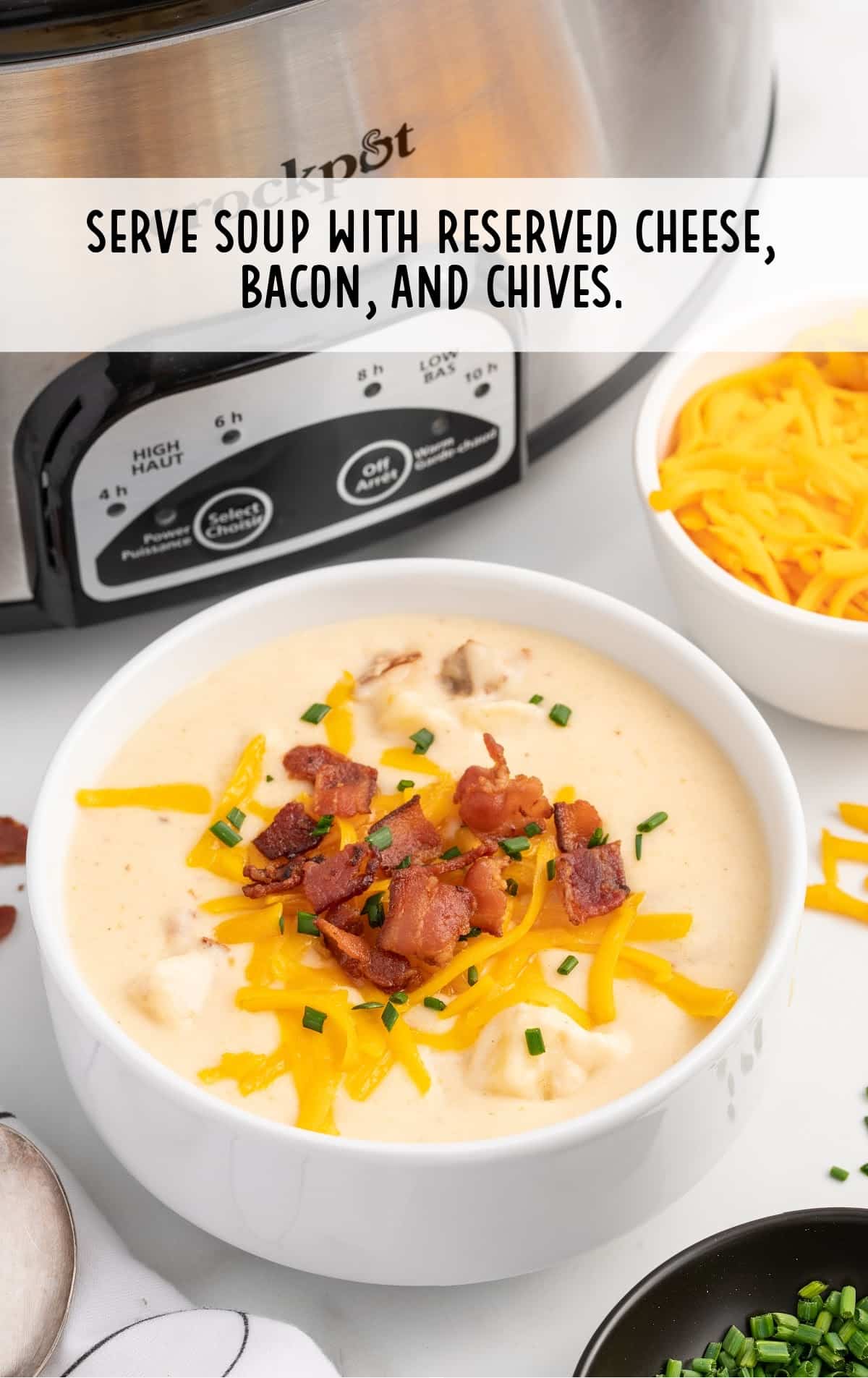 Crockpot Potato Soup in a bowl, served with cheese, bacon and chives