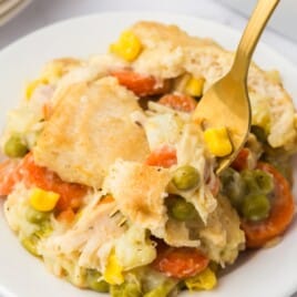 A plate of chicken pot pie with a fork in it.