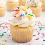 A mini cupcake with vanilla frosting and sprinkles.