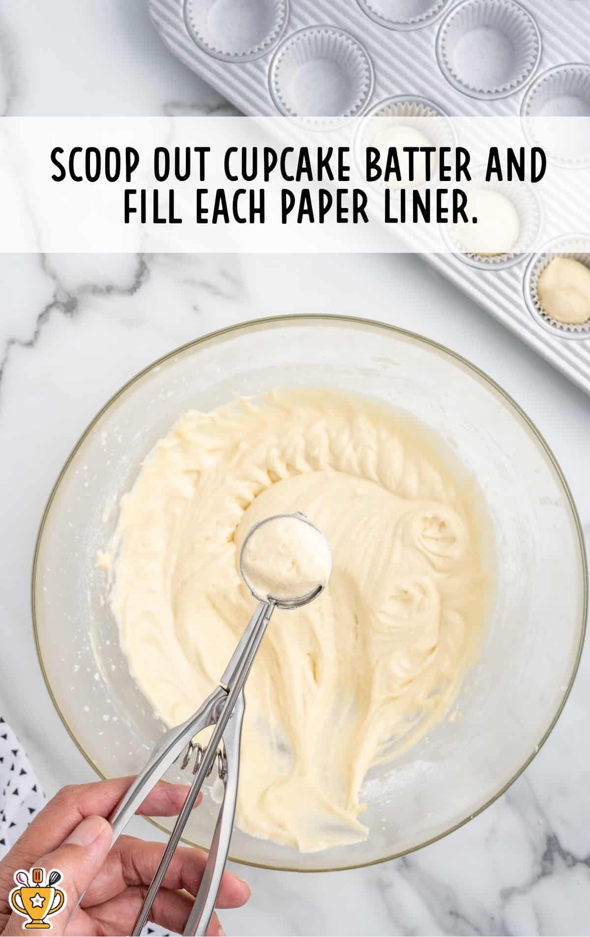 Cupcake batter in a bowl, scooped out with a portioning scoop.