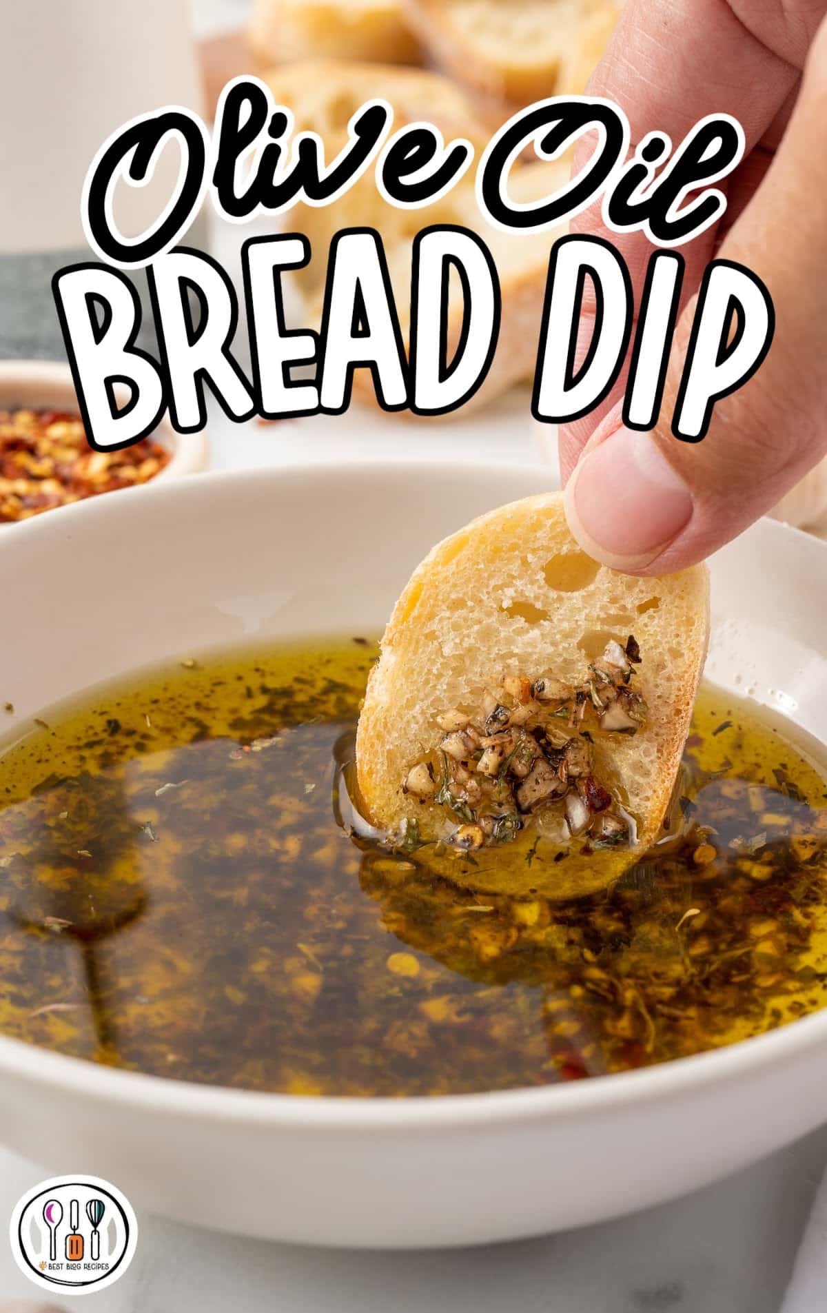 A person is dipping a piece of bread into Olive Oil Bread Dip.