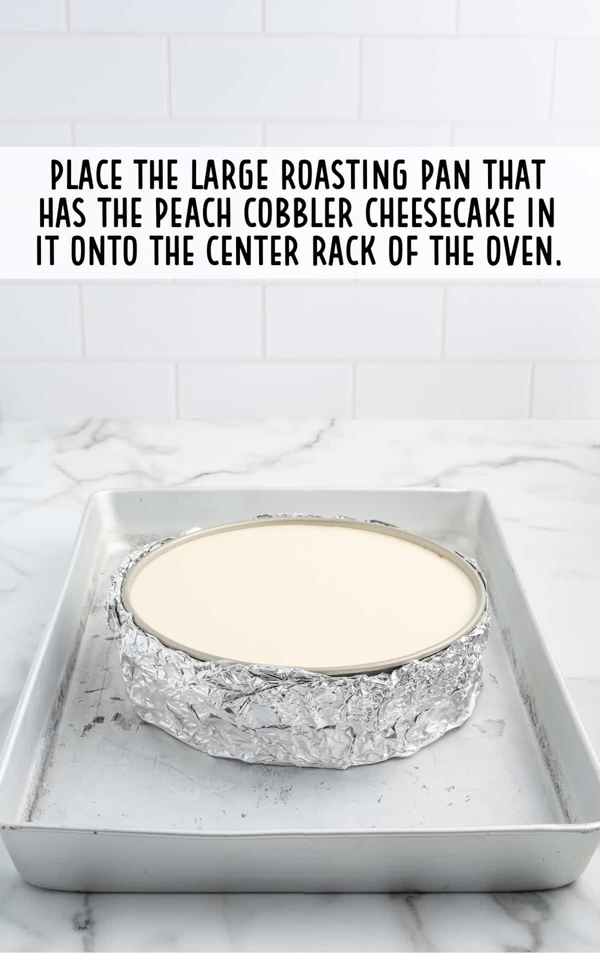 placing a large roasting pan that has the peach cobbler cheesecake in it onto the center rack of the oven