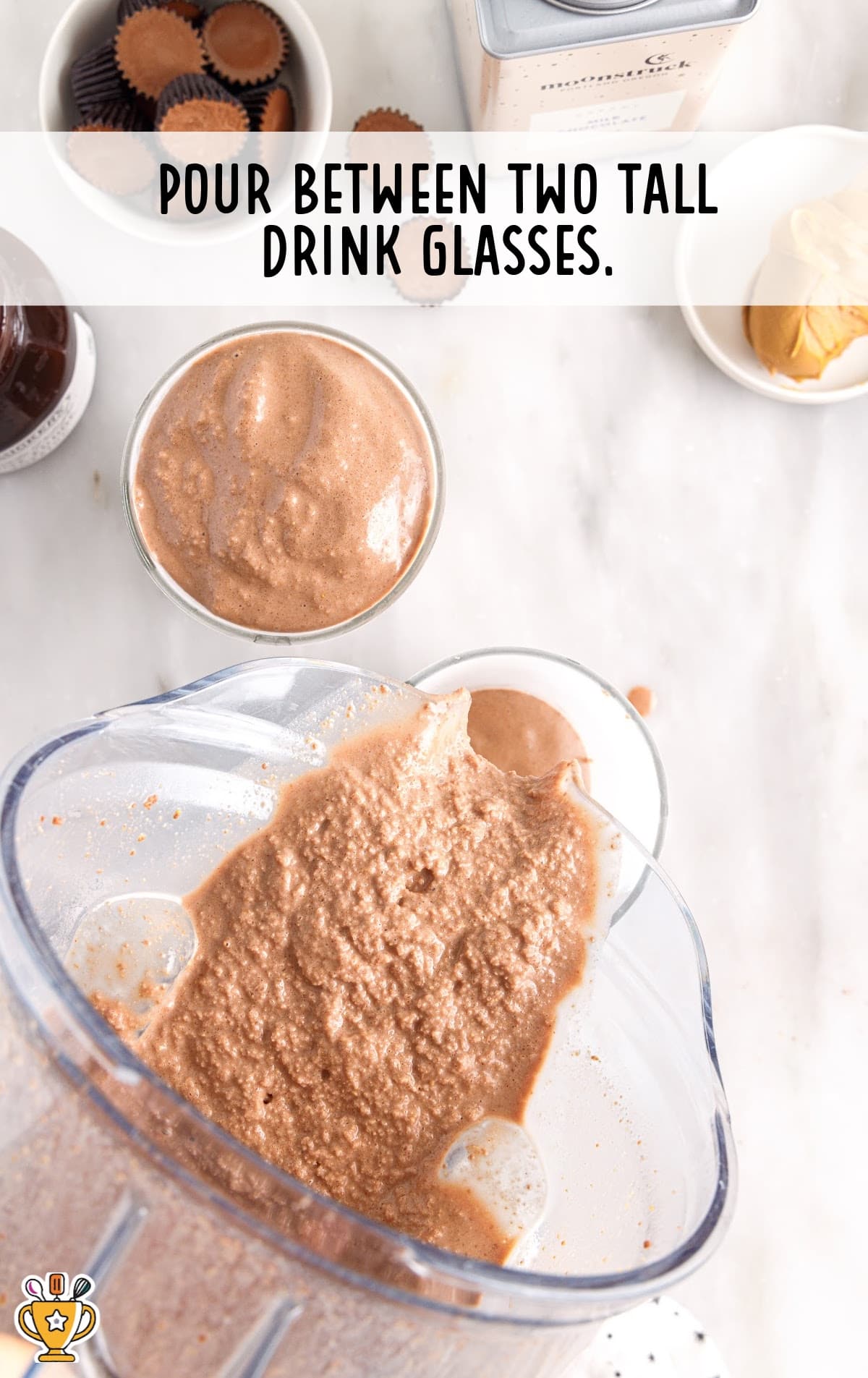 Pouring Frozen Peanut Butter Hot Chocolate from the blender to two glasses