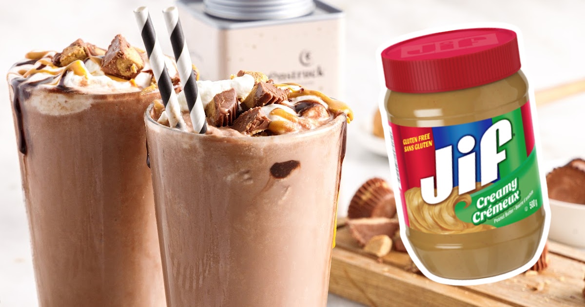 Frozen Peanut Butter Hot Chocolate in glasses with straws and a peanut butter jar on the side
