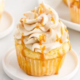 A small white plate holds one caramel cupcake.