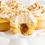 a split open Salted Caramel Cupcakes is on a white plate with other cupcakes