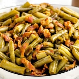 A white serving dish of smothered green beans.