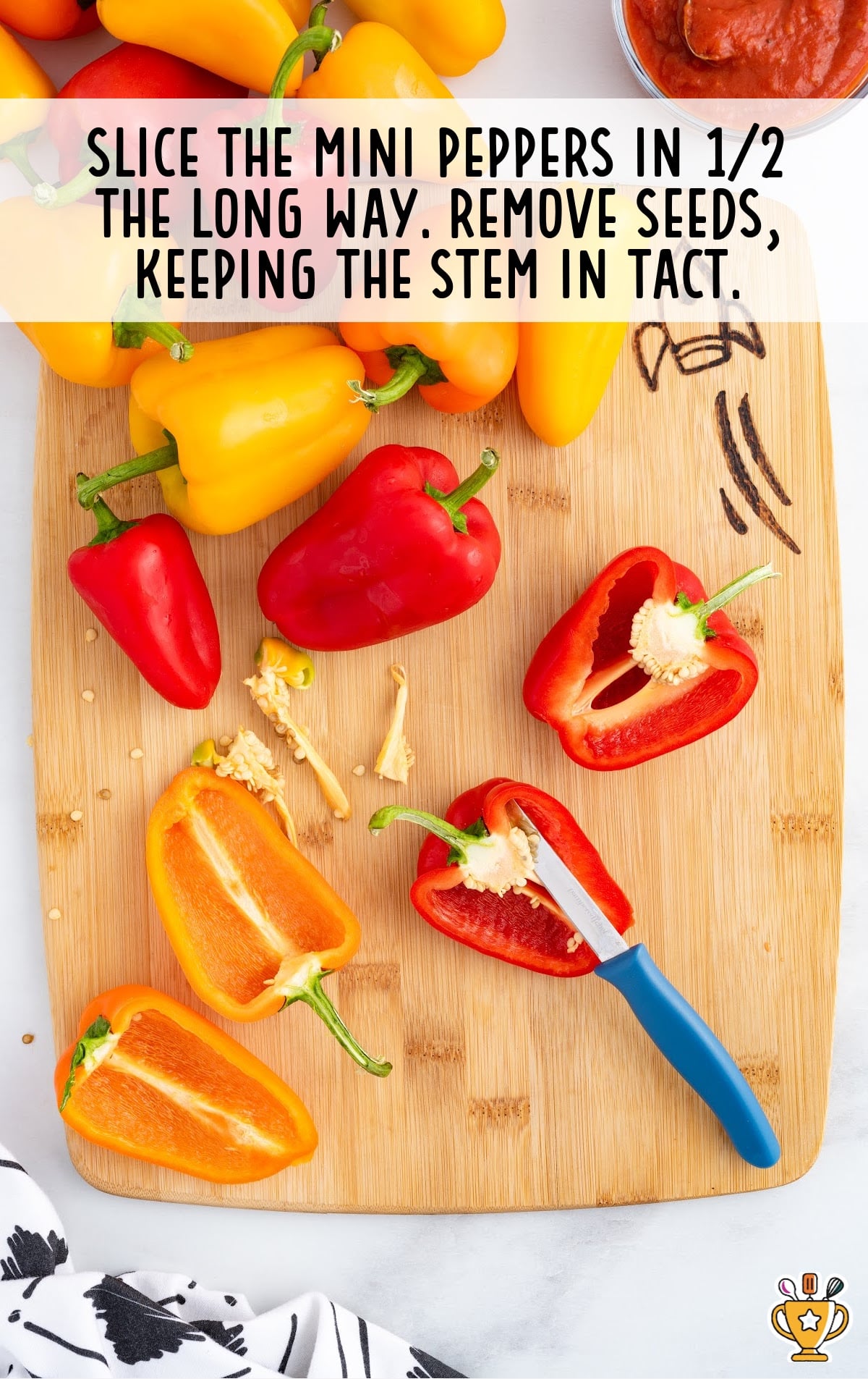 The peppers are on a cutting board and the seeds are being cleaned out.