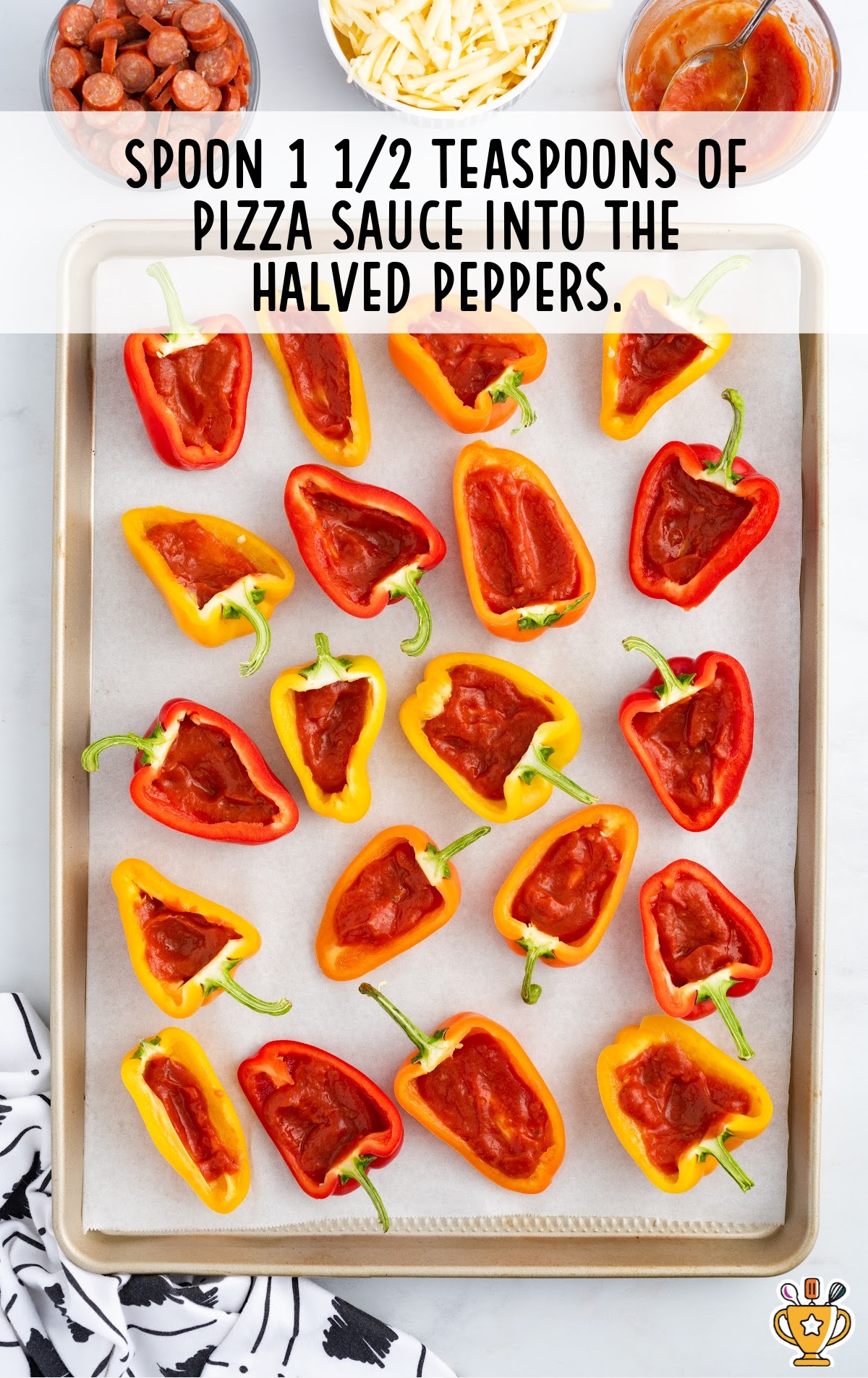 A baking tray of peppers cut out with sauce inside.