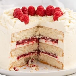 White Chocolate Raspberry Cake on a white plate with a piece missing