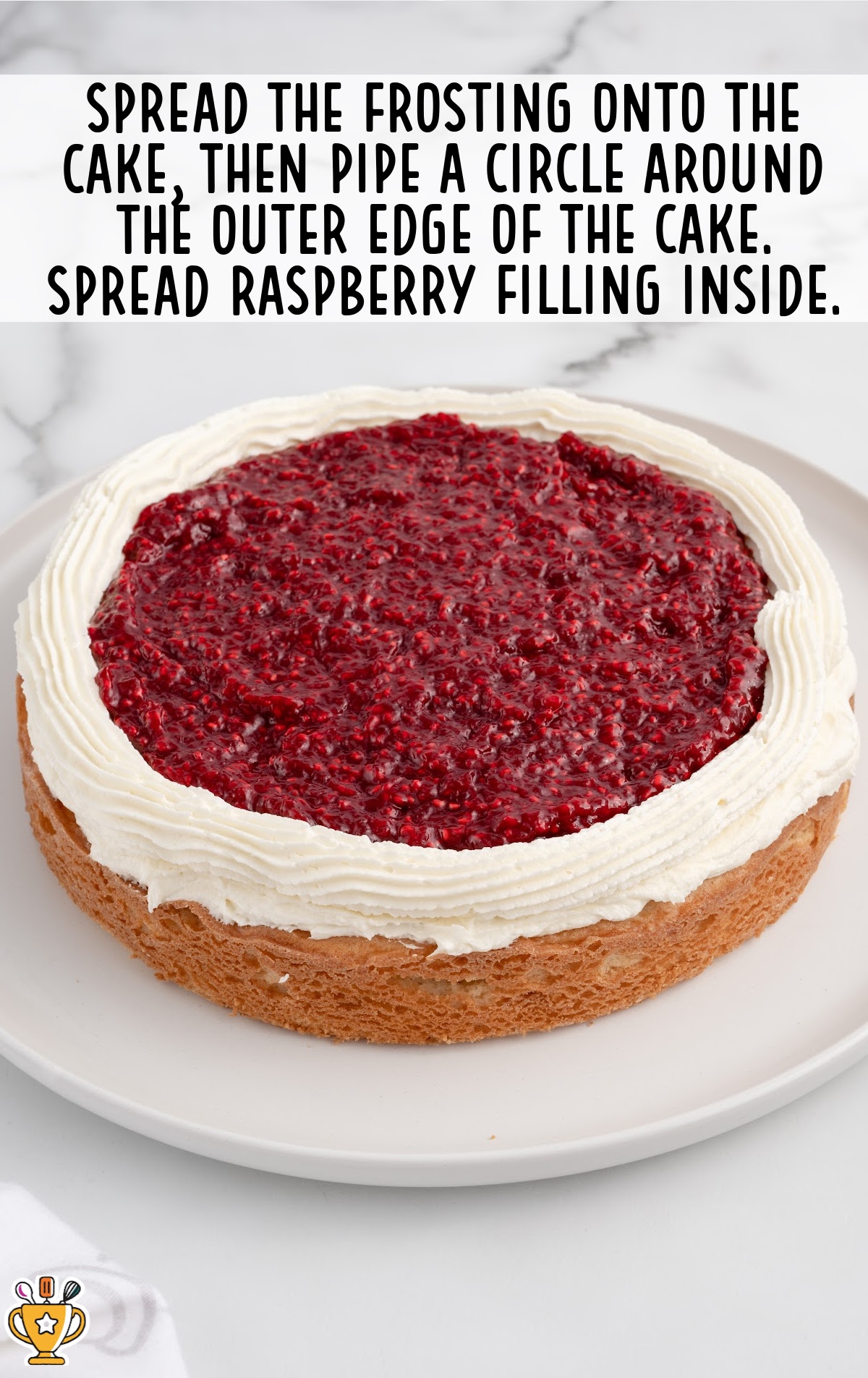 frosting spread on the cake and a circle pipped around the outer edge of the cake, with the raspberry filling inside