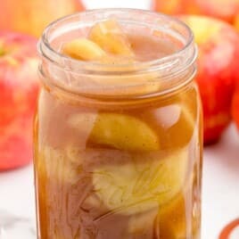Apple Pie Filling Recipe in the jar and a bunch of apples behind it