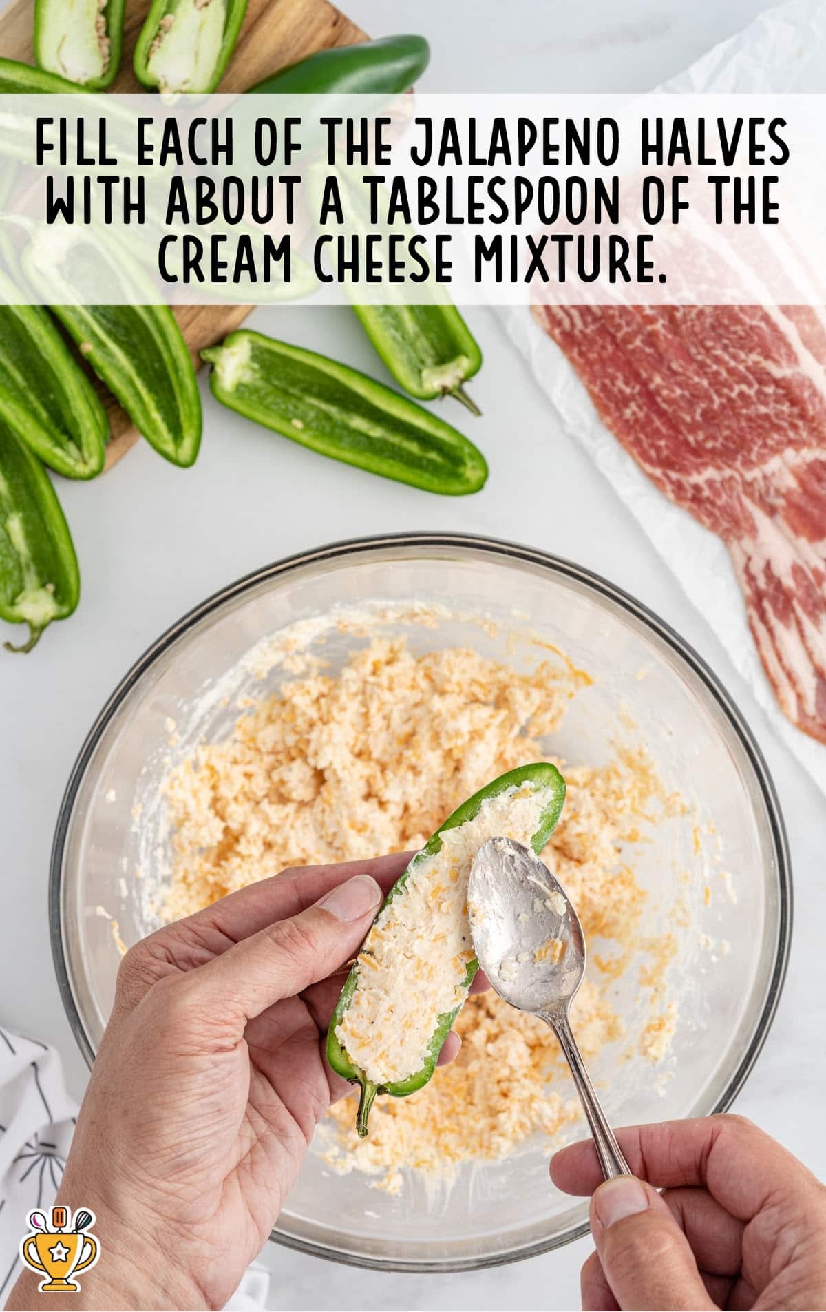 A person is using a spoon to scoop the cheese mixture into the sliced jalapeno peppers.