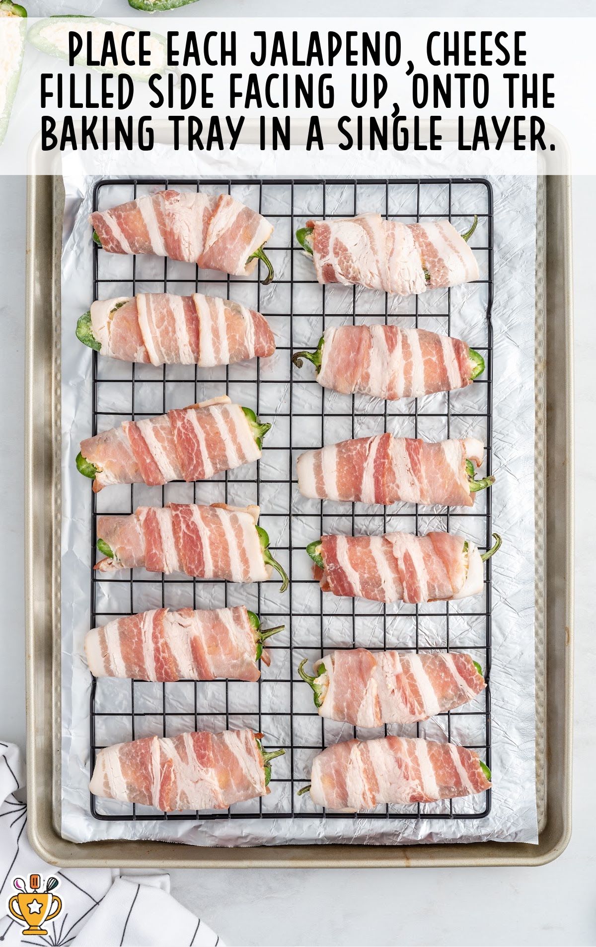 the bacon wrapped peppers are on a baking tray covered in parchment paper and a baking rack.