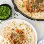 A skillet of fettuccini alfredo beside a plate of pasta and chicken.