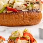 Chicken Cheesesteak sandwiches on parchment and one is cut open.