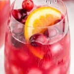 Christmas Punch in a tall glass with fruit garnishes.