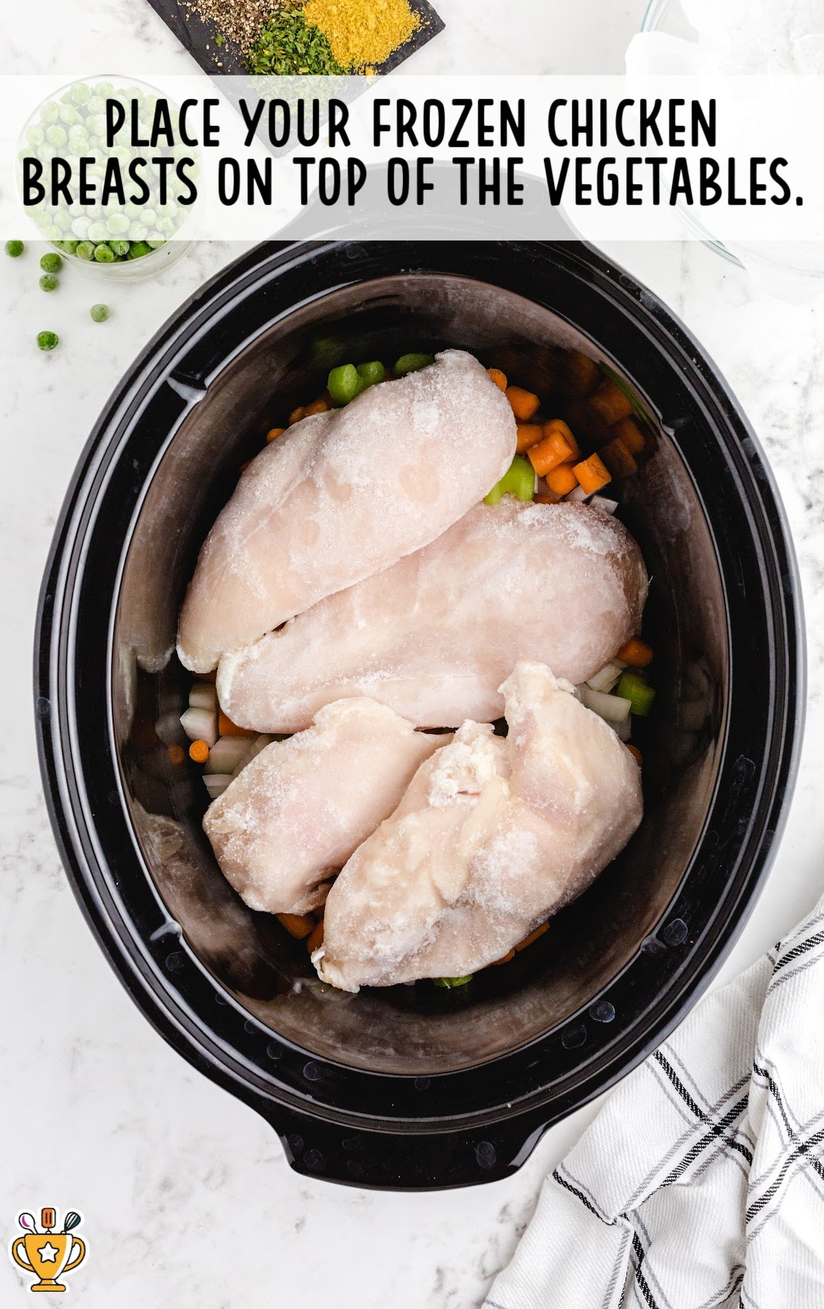 frozen chicken placed on top of vegetables in the crockpot