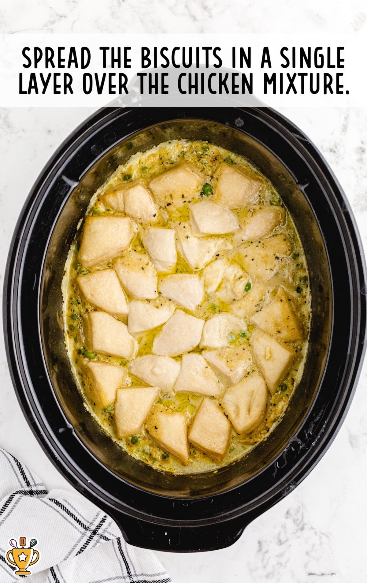 biscuits spread over the chicken mixture in a crockpot