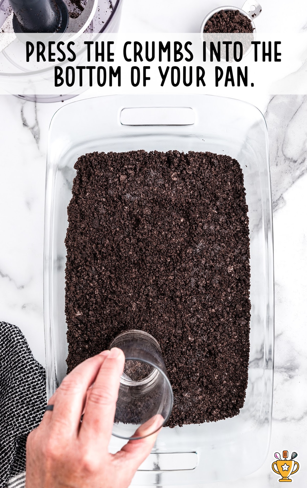 A glass baking pan with the oreo cookie crust pressed into the bottom.