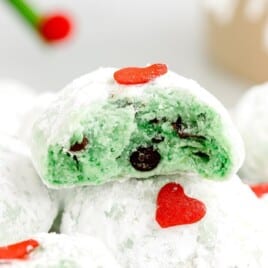 a bunch of Grinch Snowball Cookies with one cookie cut in half on top of the others