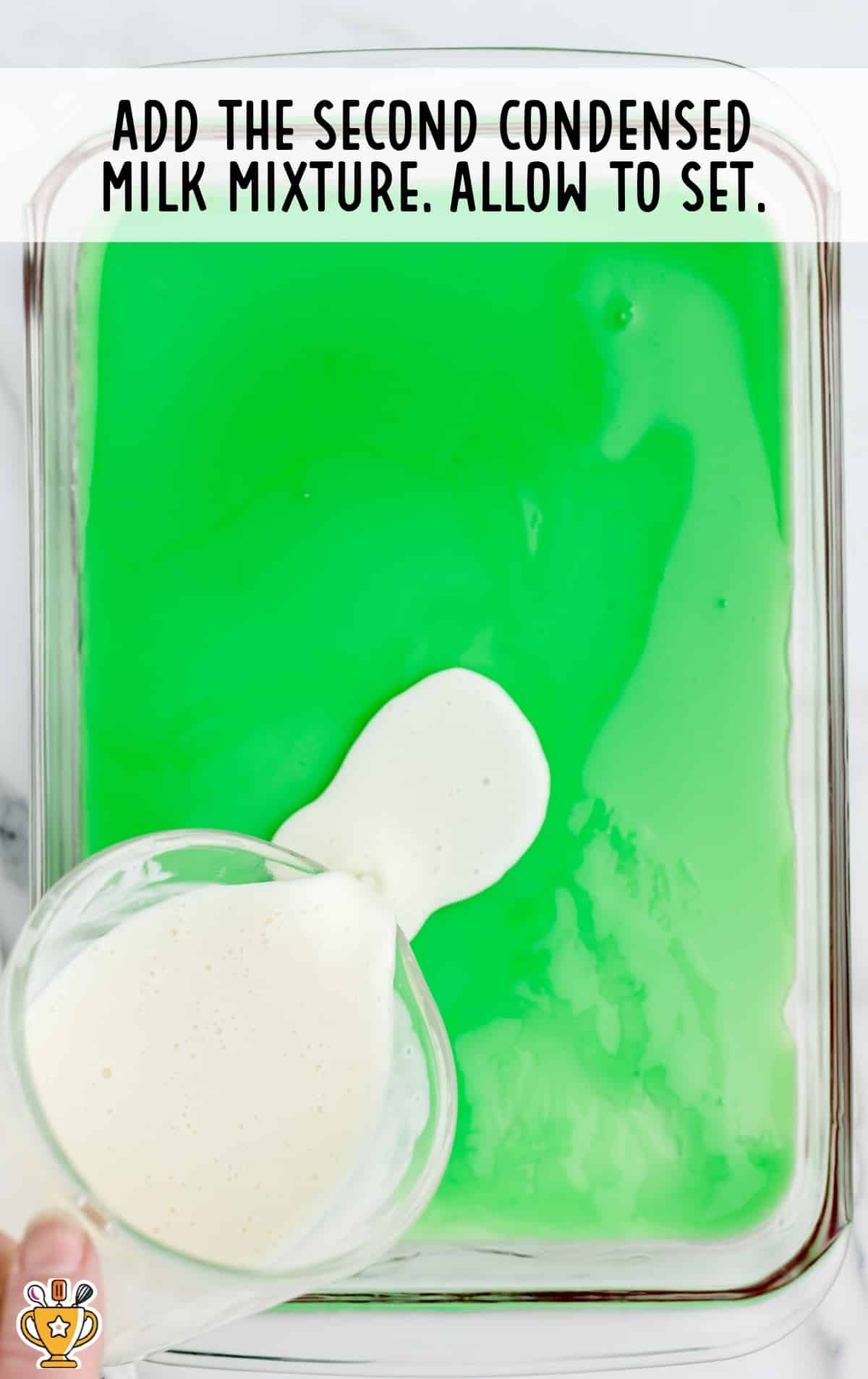 the second layer of condensed milk is poured over the lime jello.
