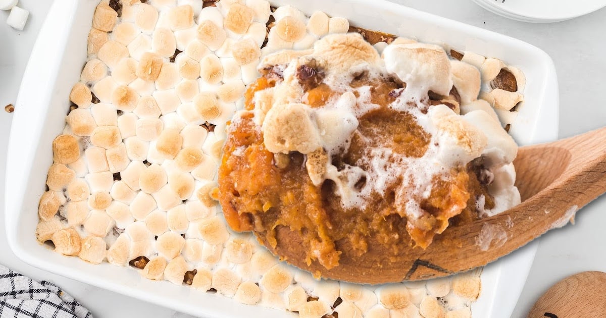 Sweet Potato Casserole in a baking tin and wooden spoon holding some of it