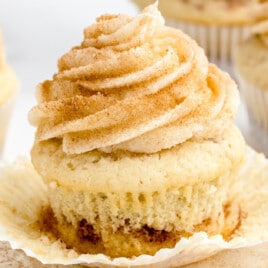 a Cinnamon Cupcake on a plate with a bunch others at the back