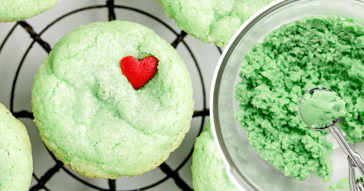a Grinch Cookie on a rack and some icing sugar in a bowl
