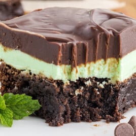 A mint brownie on a plate with a bite out of it.